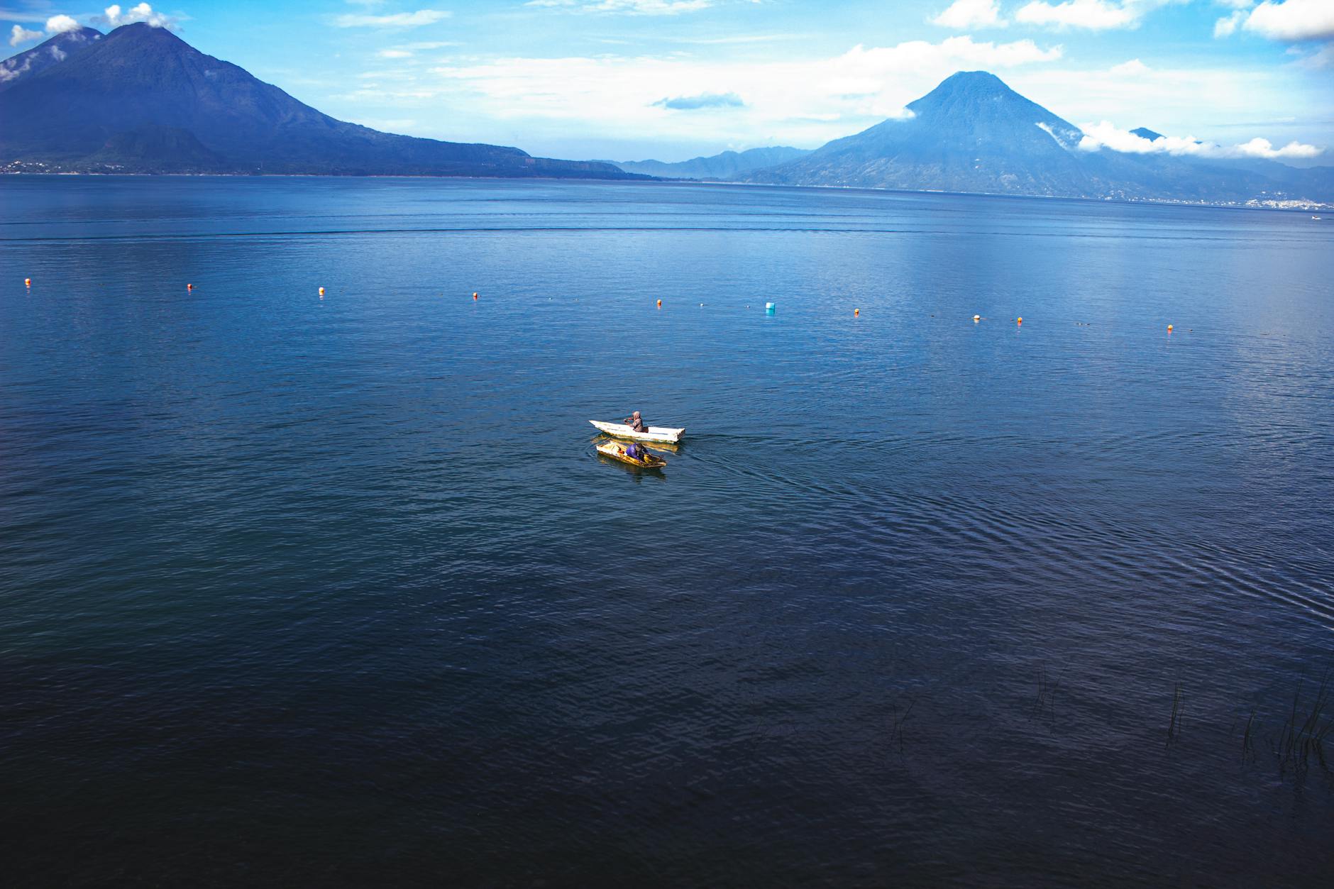 Łódź na spokojnej tafli jeziora Atitlán w otoczeniu gór