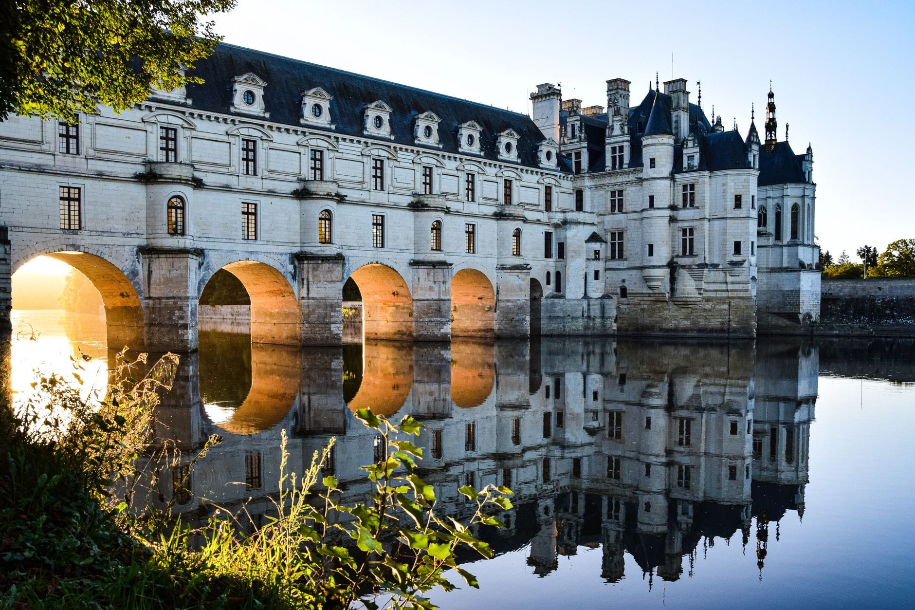 Zamek Chenonceau odbijający się w rzece Cher o wschodzie słońca